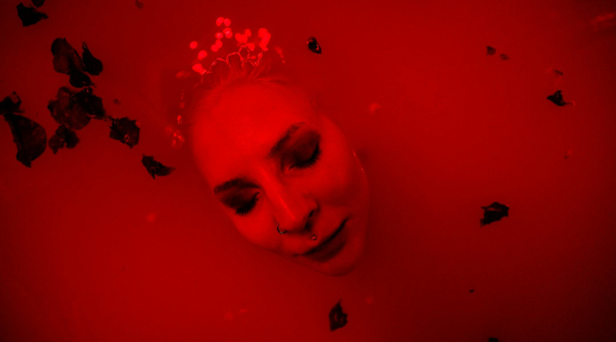 Fotografi av Pernille Azoras ansikt som dukker opp av rødfarget vann