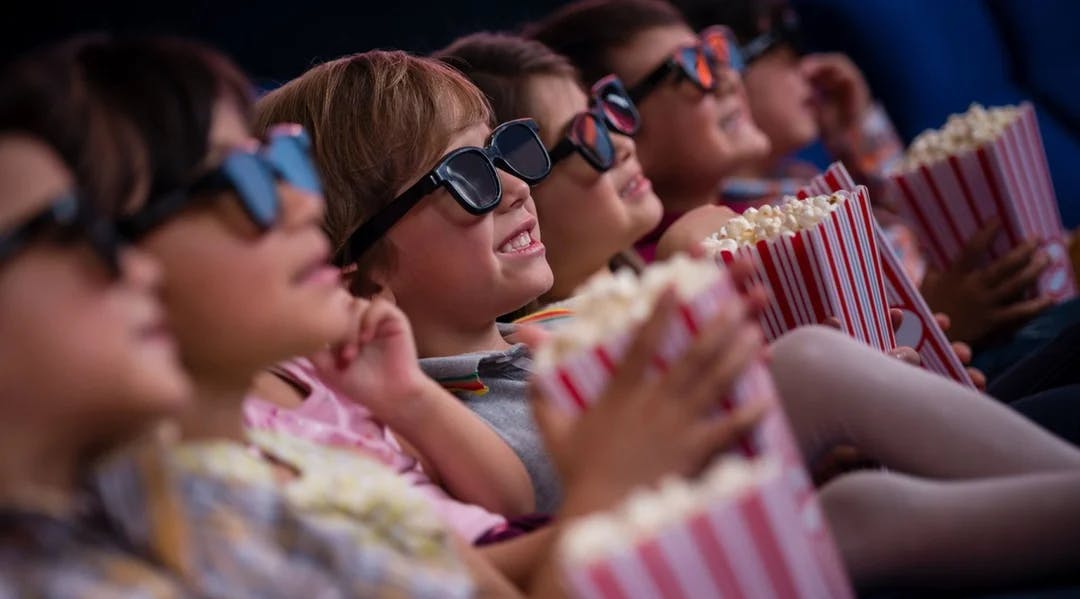 Barn ser på kino med popkorn og 3D-briller