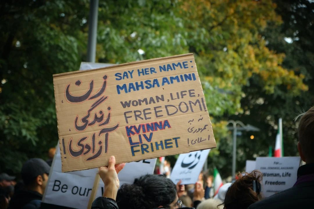 Fotografi av protestplakat med teksten "Kvinne, liv, frihet" og "Say her name: Mahsa Amini"