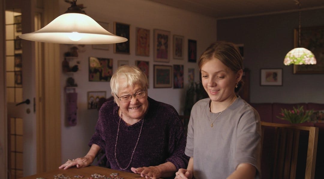 En eldre dame pusler puslespill med en ung jente