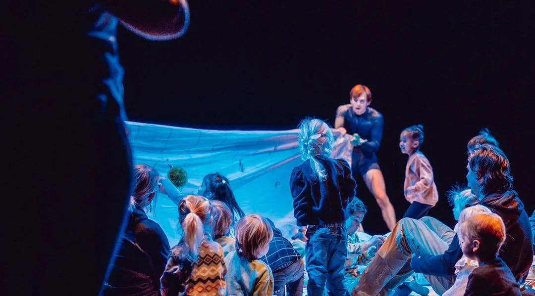 Barn sitter samlet rundt teaterscenografi med undervannstema